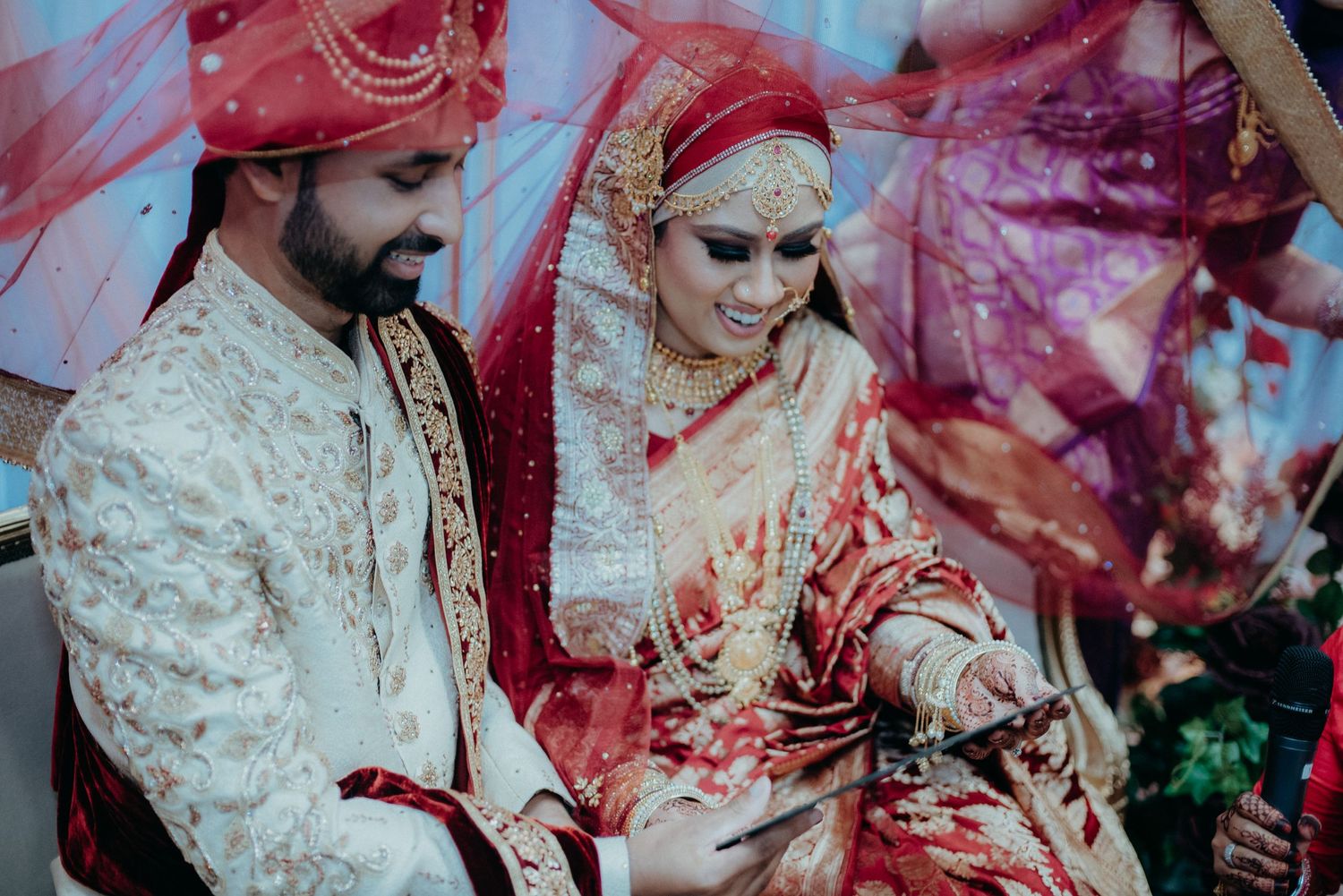 Traditional wedding ceremony with couple in ornate red and cream cultural attire.