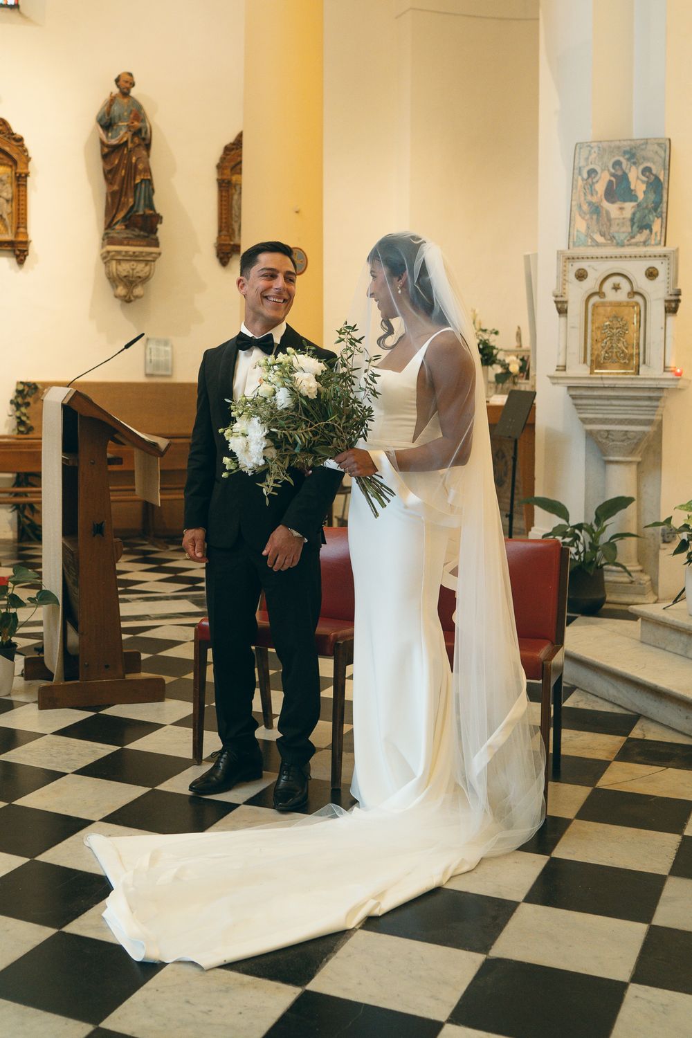 Elegant church wedding with black and white checkered floor and religious artwork.