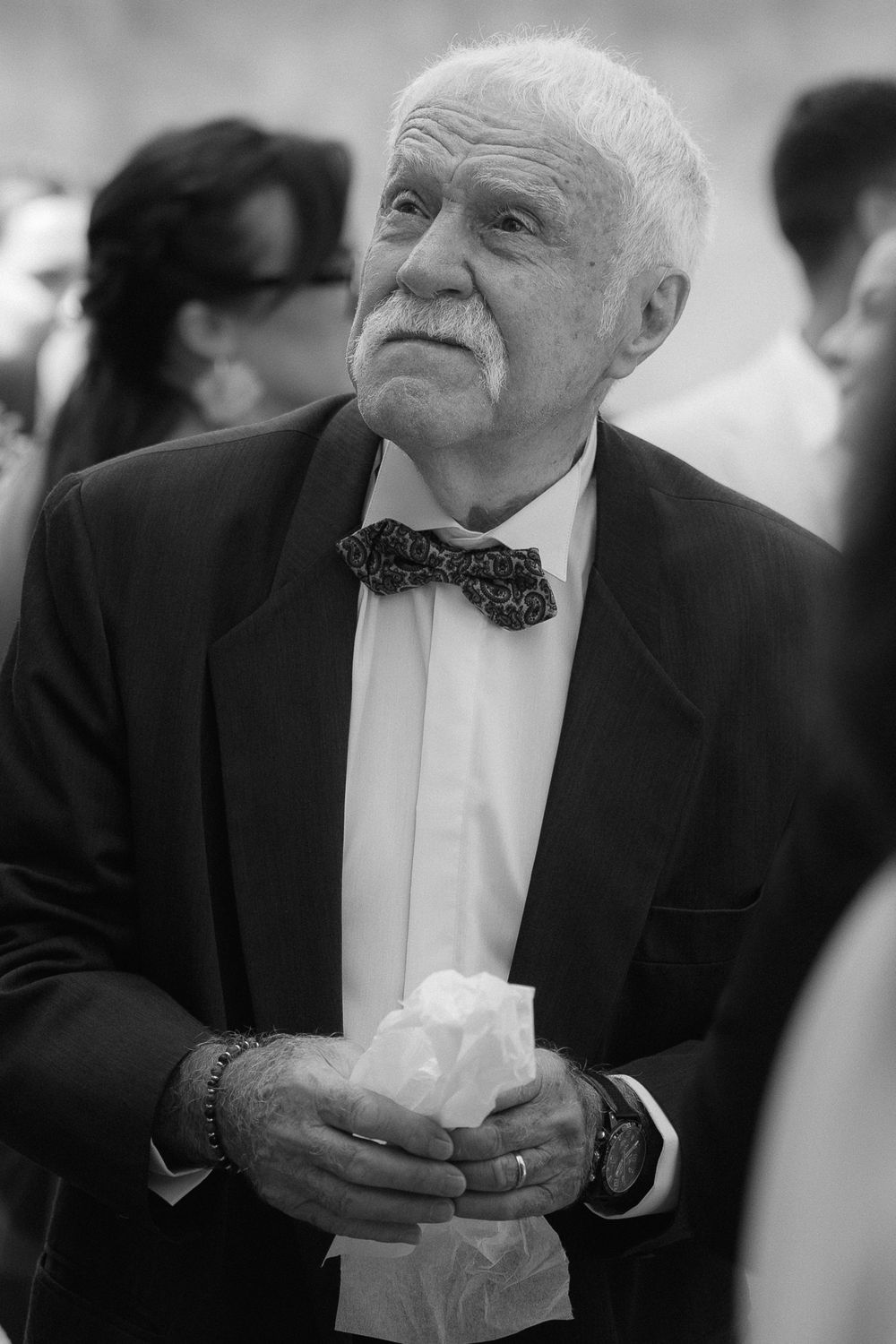 Elderly guest in formal attire enjoying a moment at an elegant event.