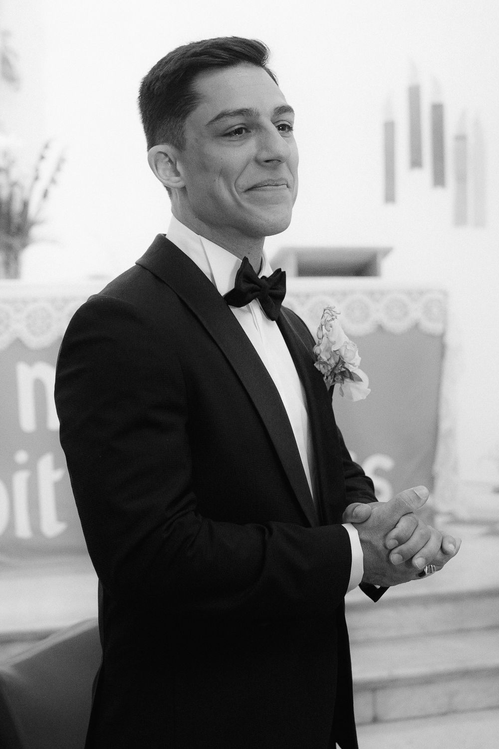 A person in a black tuxedo and bow tie smiles during a formal event.