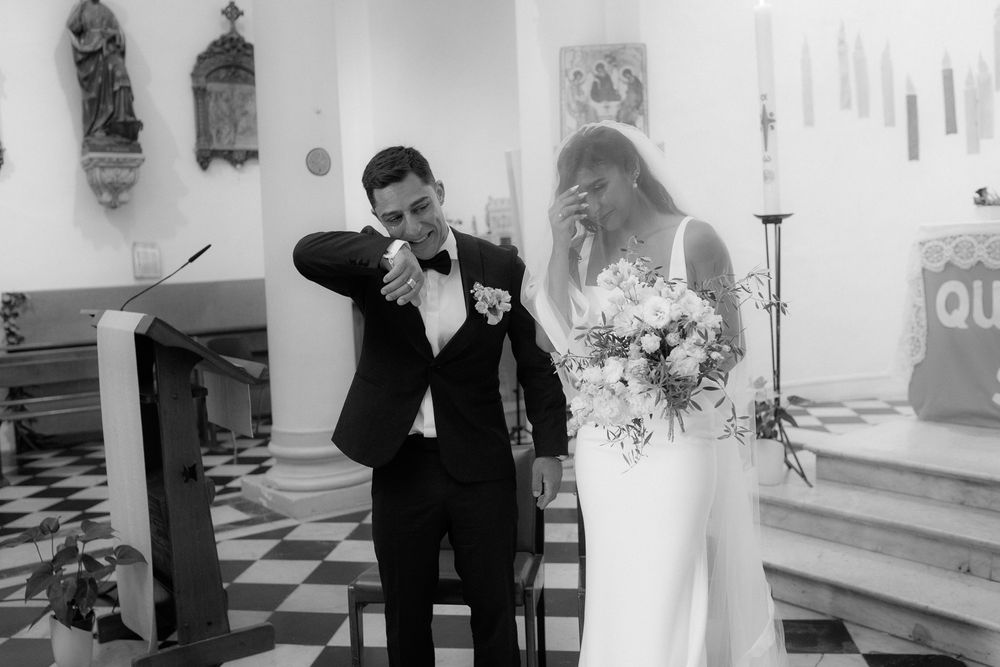 Elegant wedding ceremony taking place in a church with religious artwork on walls.