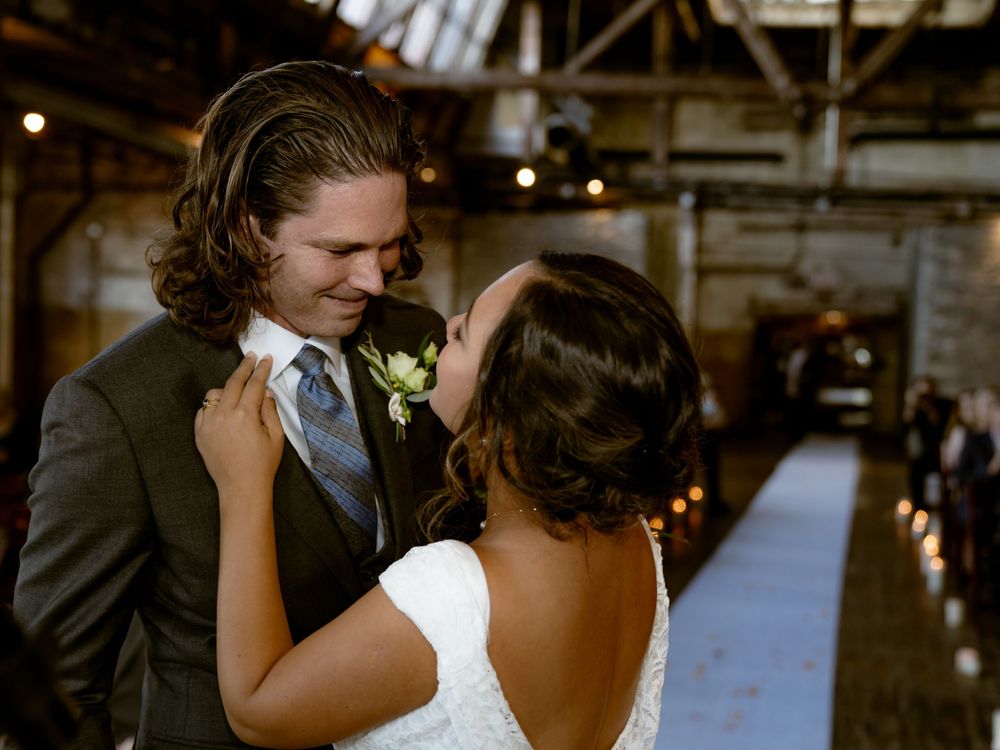 A romantic moment between newlyweds in an industrial-style venue with warm lighting.
