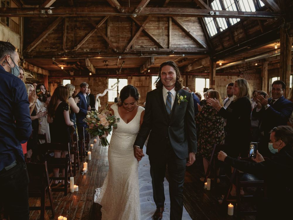 Wedding ceremony recessional in a rustic industrial venue with exposed wooden beams.