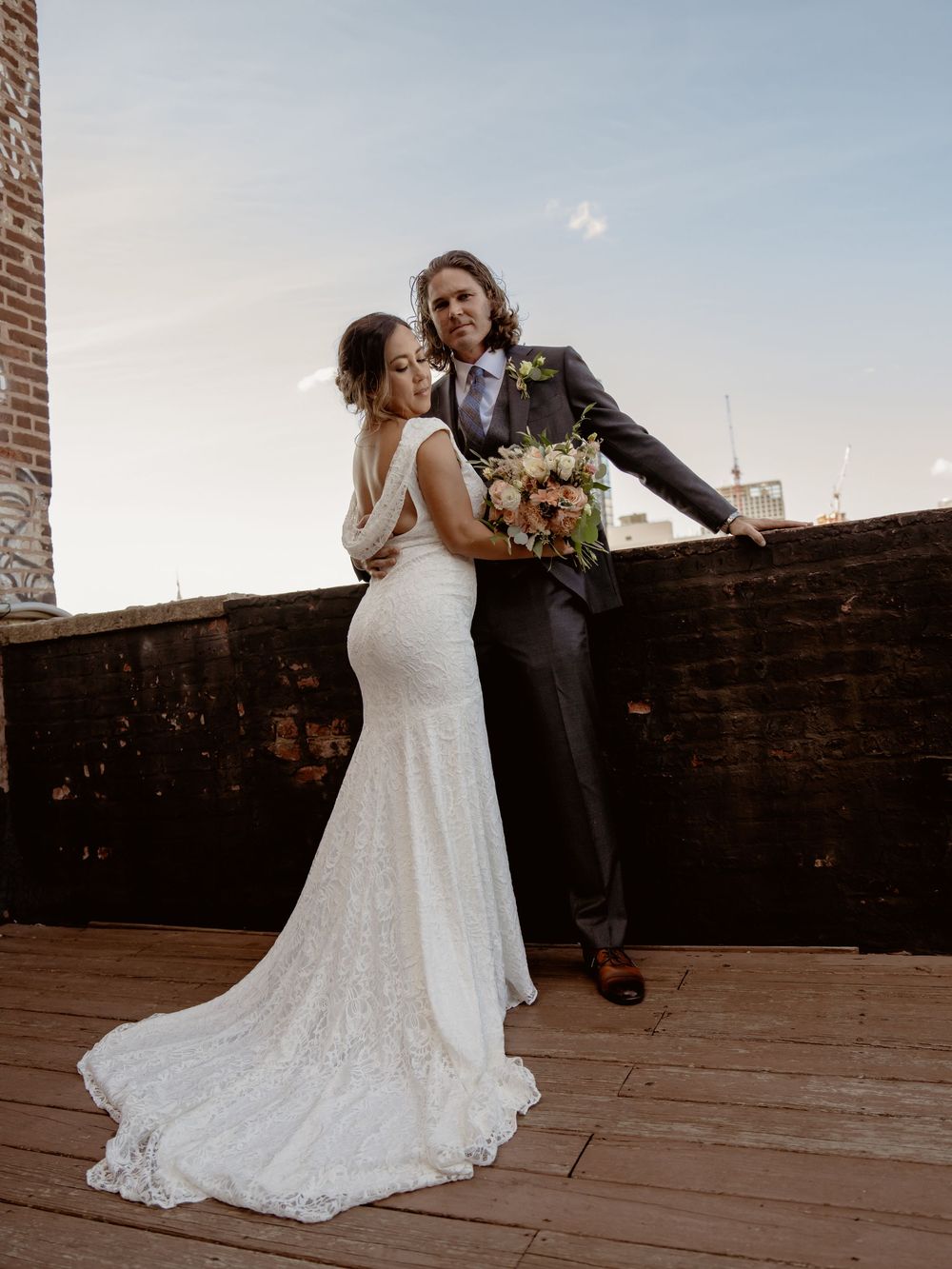 An intimate wedding portrait on a rooftop deck with a fitted lace gown and formal suit.