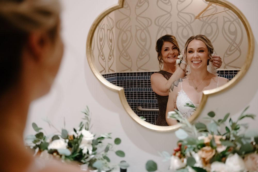 A collection of oval mirrors decorated with greenery and floral arrangements at a wedding venue.