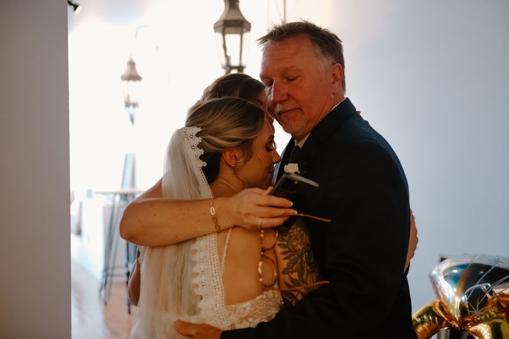 A couple shares an intimate moment during their wedding ceremony in a bright, white-walled venue.