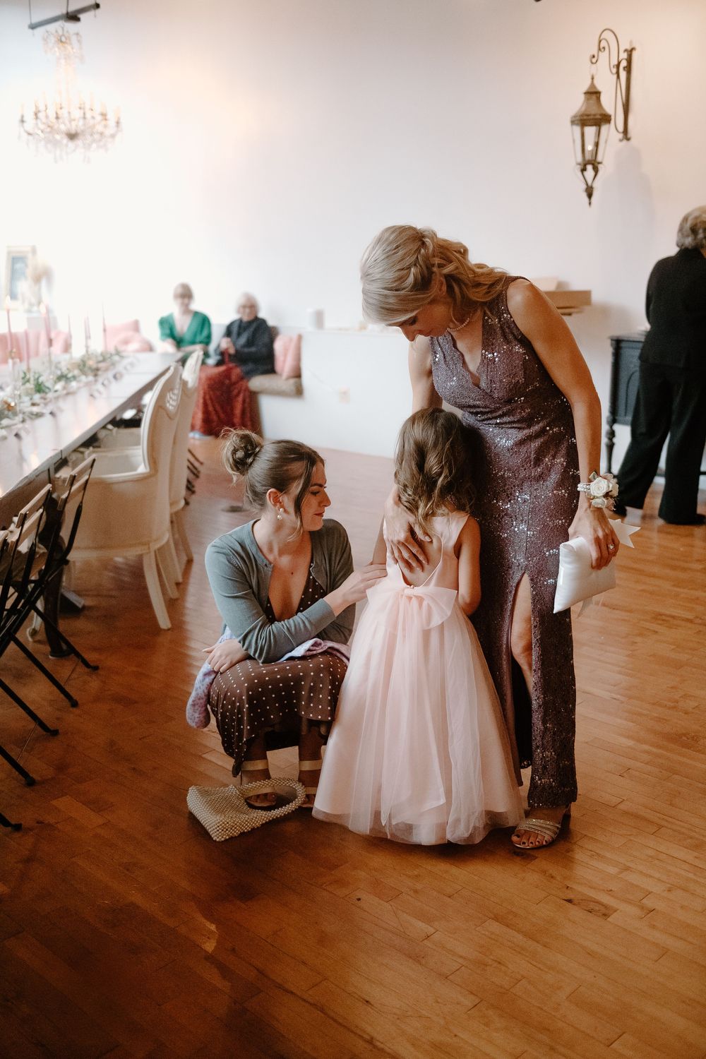 An emotional moment at a wedding as two people share a tender embrace on a hardwood floor.