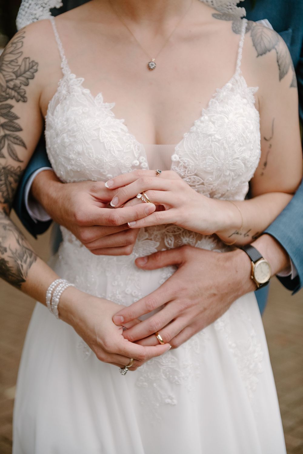 Close-up wedding photos showing hands with rings and delicate white lace details on a bridal gown.