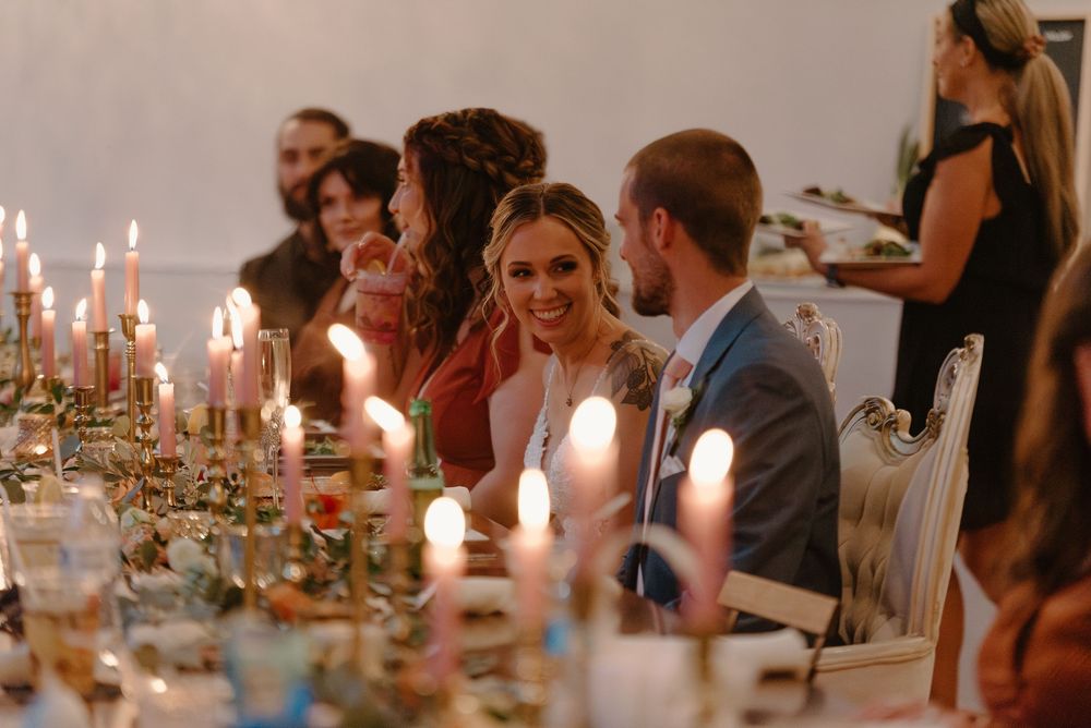 Wedding guests dine at an elegantly decorated candlelit reception table with floral centerpieces and glowing ambiance.
