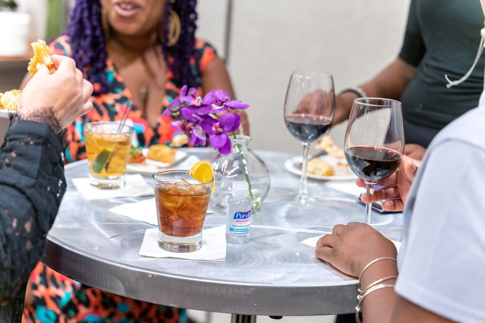 People enjoying a social gathering with summer cocktails and beverages on a patio dining table.