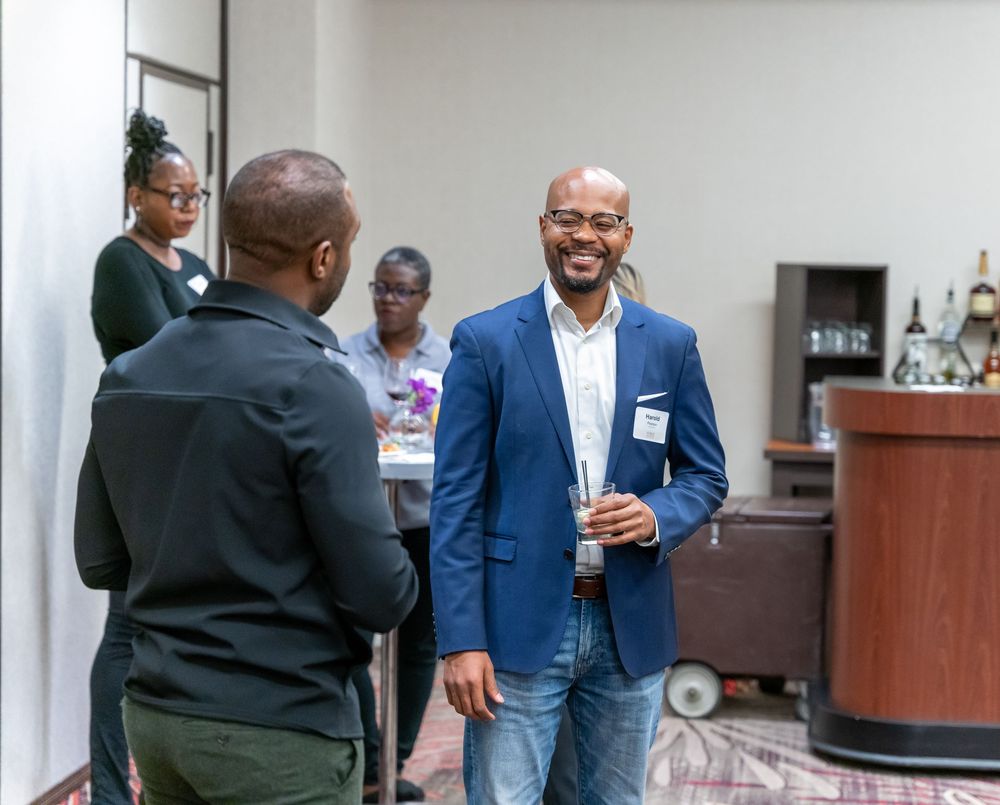 People in business casual attire engaging in conversation at an indoor networking event.