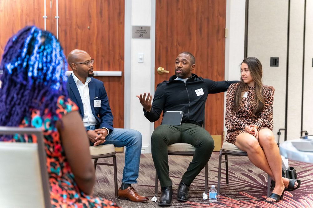 People sitting and having conversations in various poses at what appears to be a business or networking event.
