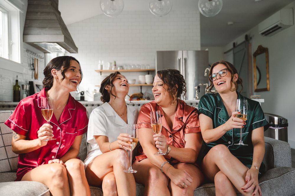 Bride and bridesmaids laughing and enjoying champagne together in a bright kitchen setting at Warwick, NY.