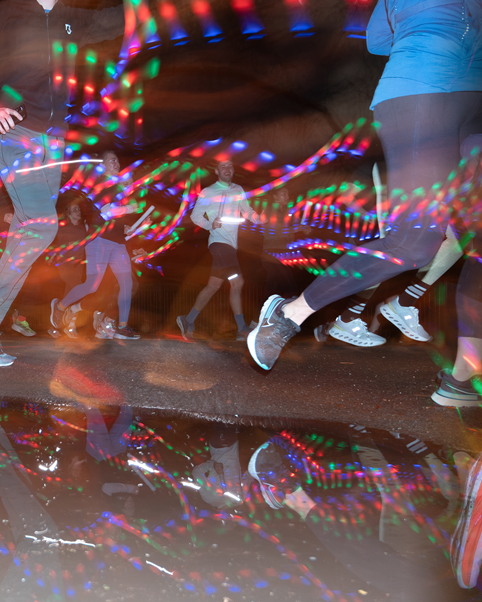 Long exposure of runners running on wet ground with light trails illuminating the scene.