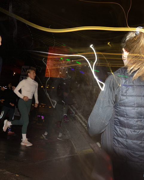 Blurred motion shot of people exercising at night with streaks of light creating dynamic patterns.