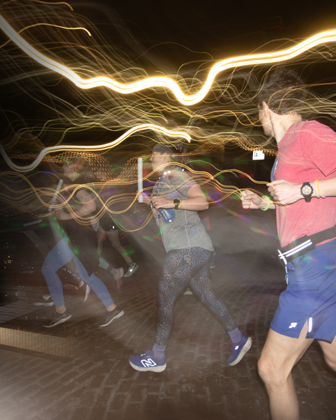 Long exposure photograph showing light trails and movement of runners at night.