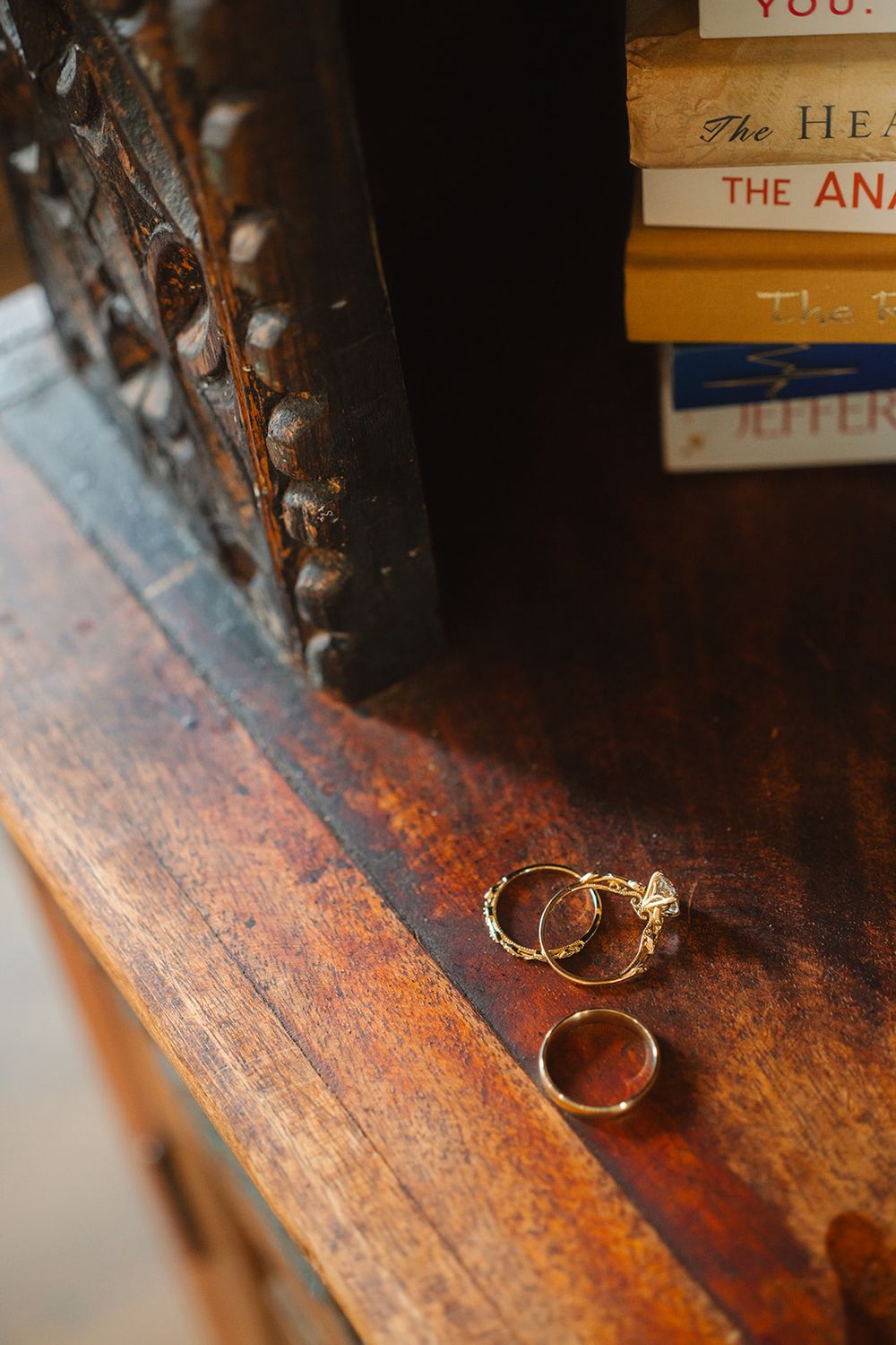 Two gold wedding rings resting on a rustic wooden surface with warm lighting.