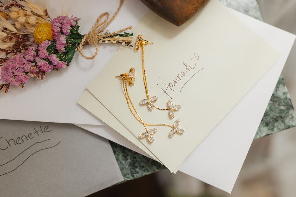 Elegant wedding invitation cards with gold accents and dried flowers on a marble surface.