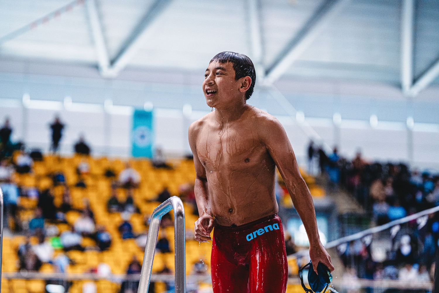 Competitive freestyle swimmers diving into a pool at the start of a race in a large indoor aquatic center.