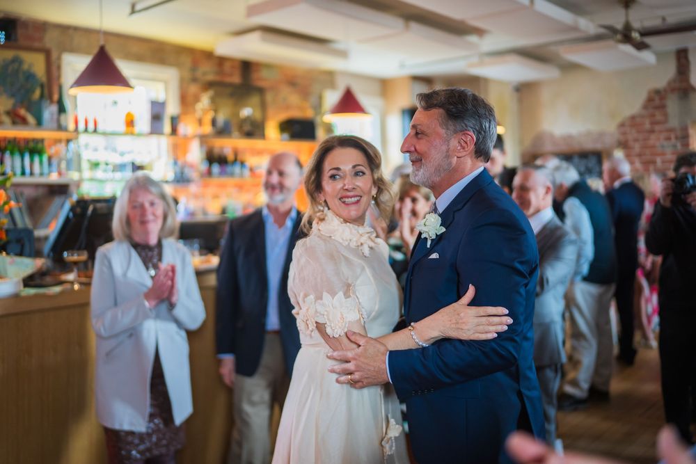 A couple shares their first dance at a rustic indoor reception venue with exposed brick walls and pendant lighting.