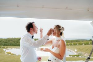 Newlyweds sharing a playful moment during their wedding toast outdoors.