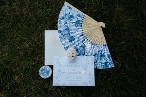 A decorative hand fan with blue floral patterns and gold accents photographed in a sequence of five actions against grass.
