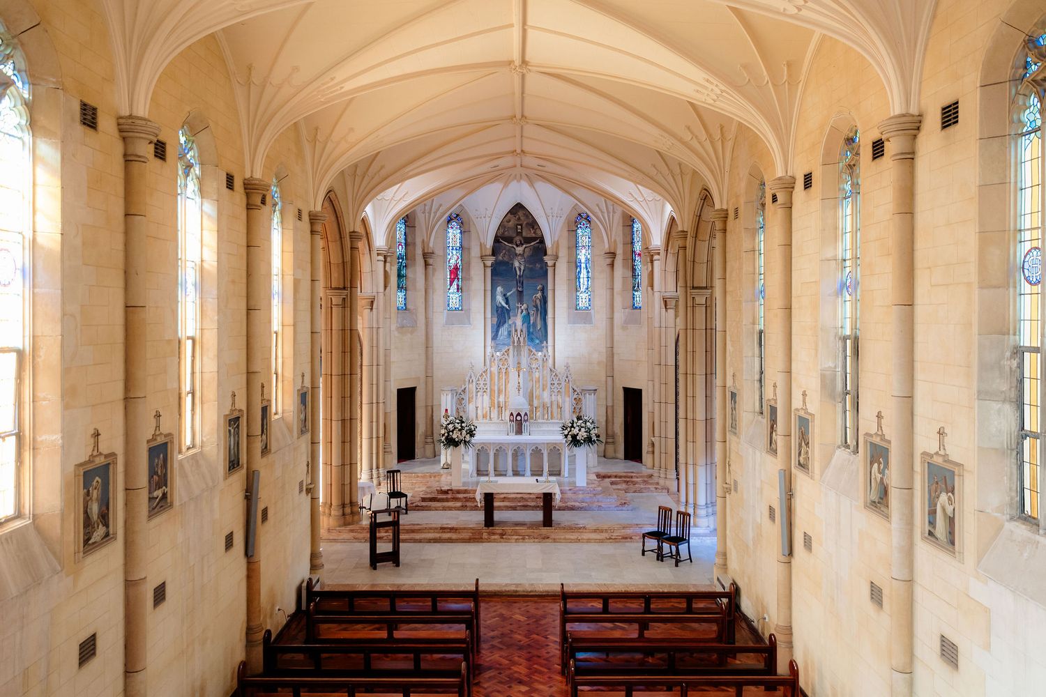 A panoramic view of a church interior with wooden pews, vaulted ceilings, and stained glass windows in a Gothic style.
