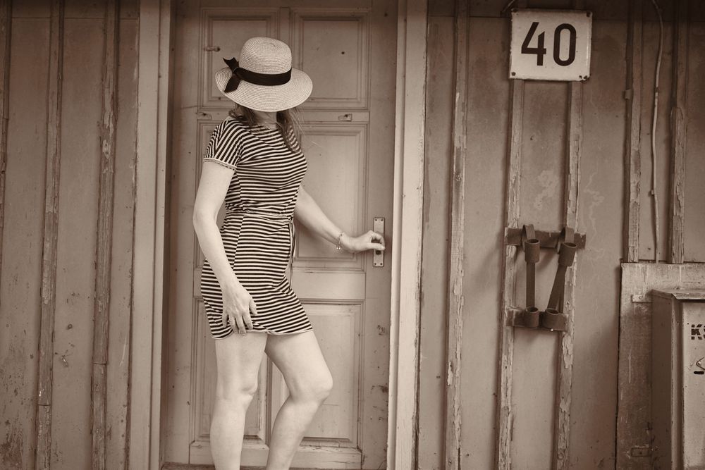 sepia portrait, vintage doorway, straw hat, moody tones, nostalgic shoot, rustic fashion, timeless editorial, natural light