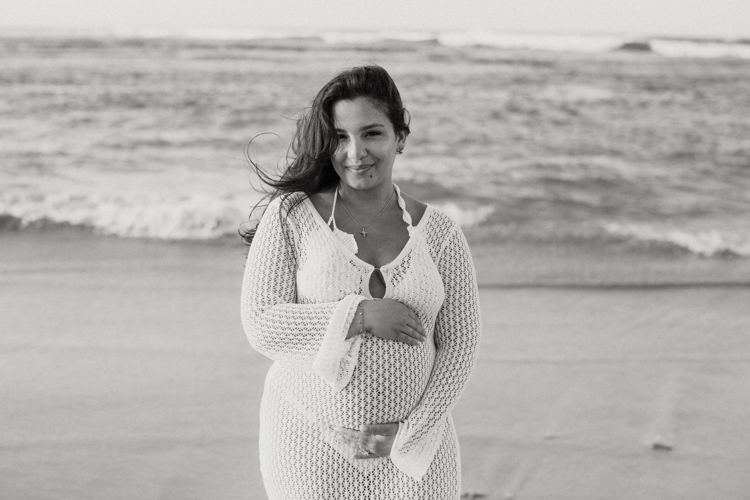 Black and white portrait on beach wearing white crochet dress.