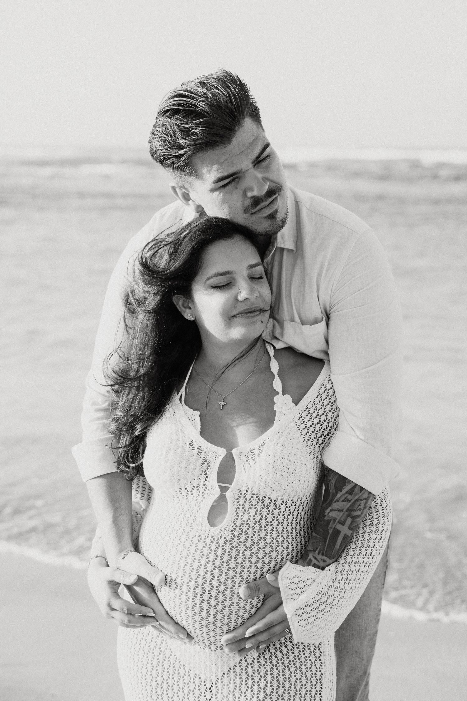 Black and white beach portrait of couple in loving embrace.