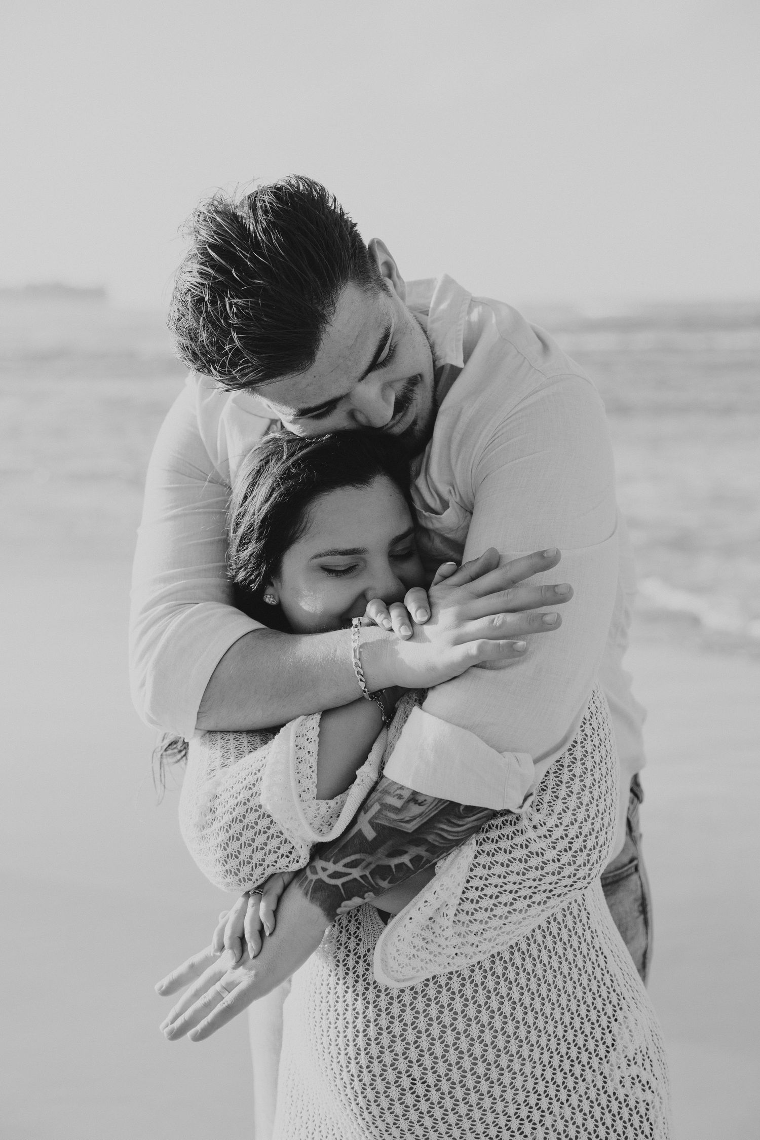 Black and white photograph of intimate moment on beach.