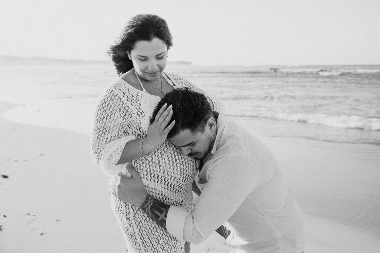 Couple sharing joyful moments during sunset beach photoshoot.