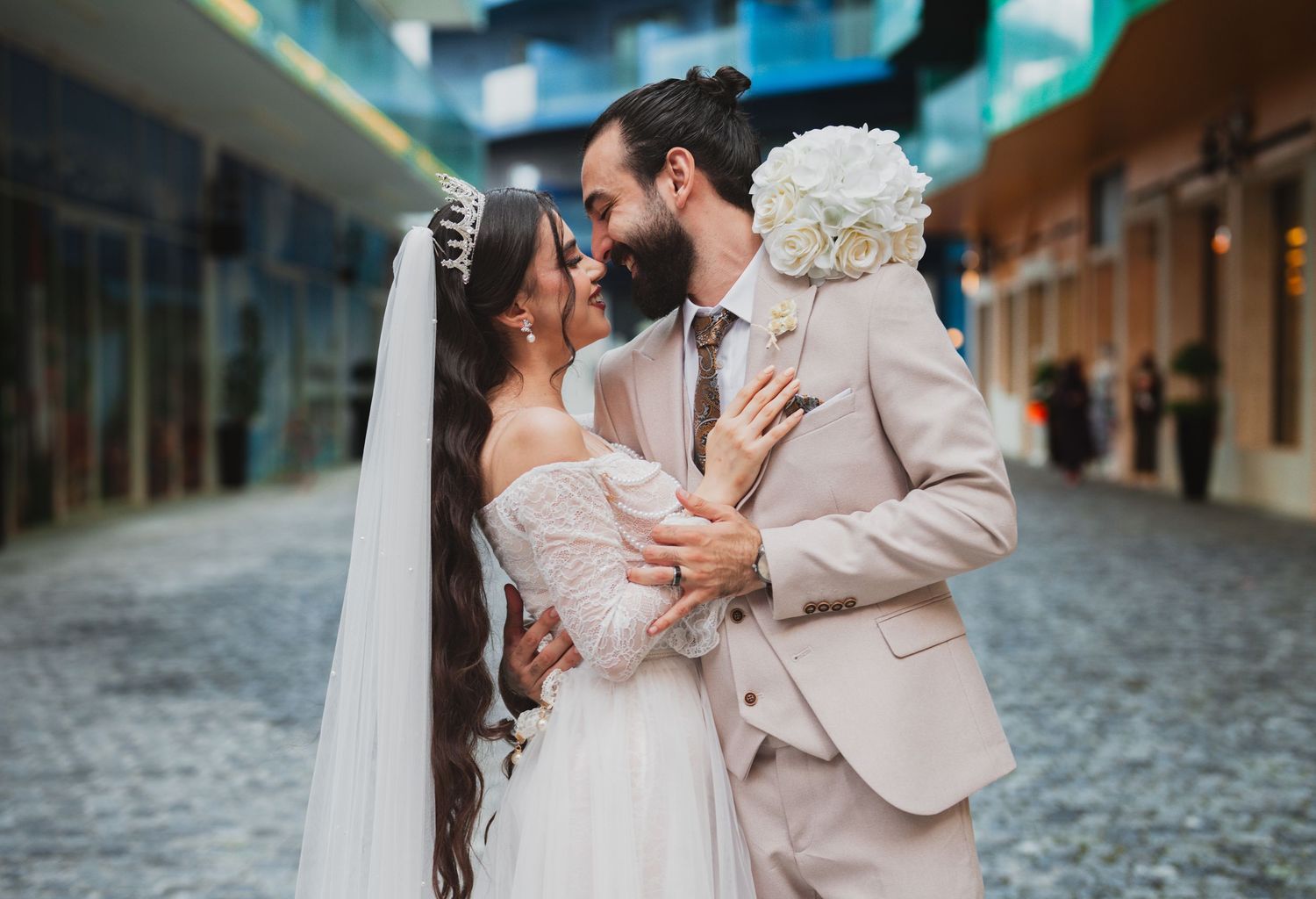 A romantic couple shares tender moments in their wedding attire on cobblestone streets during an intimate photoshoot.