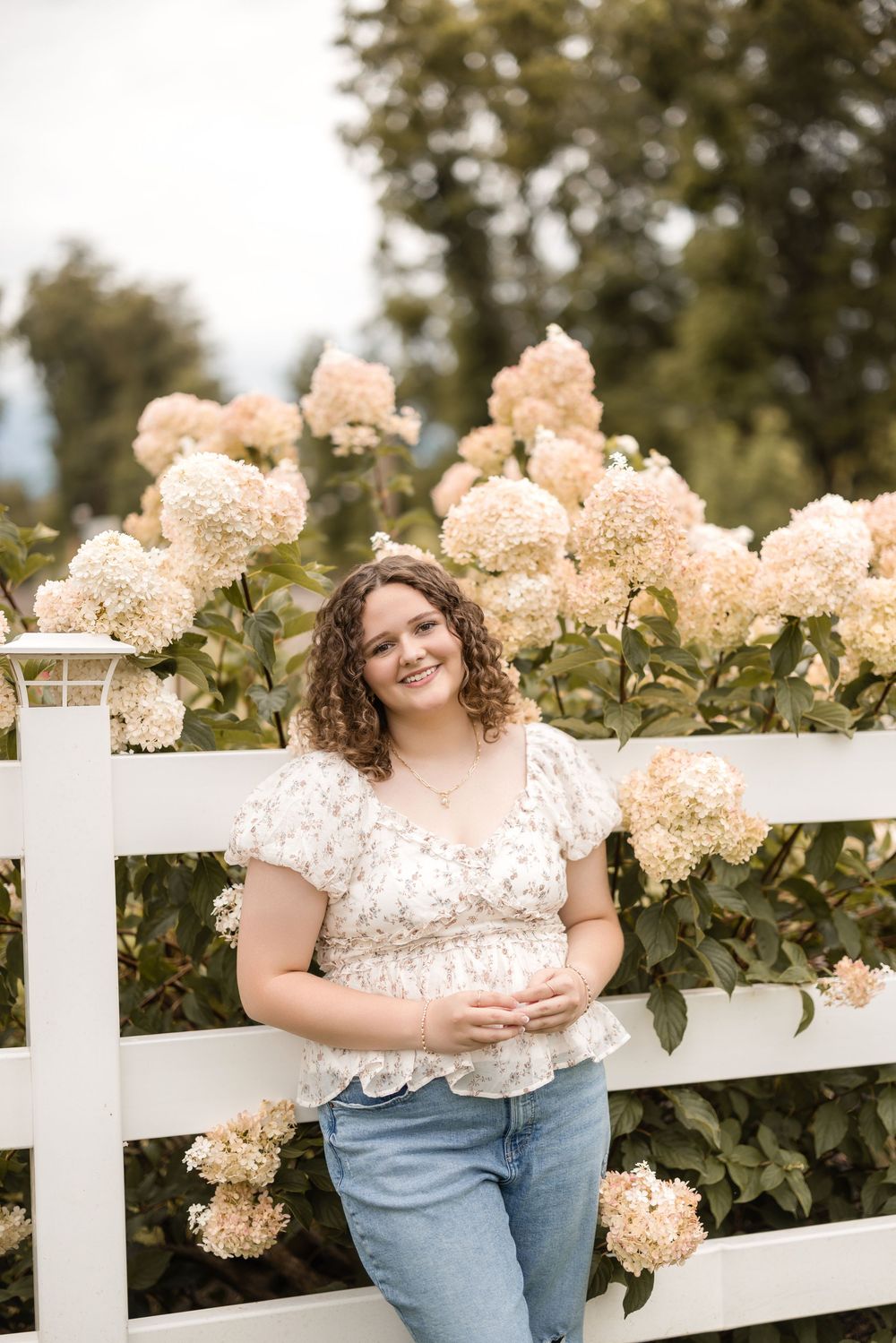 Beautiful hydrangea blooms on white fence with casual lifestyle portrait in summer garden setting.