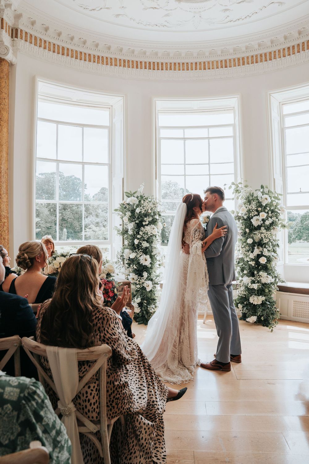 Indoor wedding ceremony at Rockbeare Manor with floral arch around window