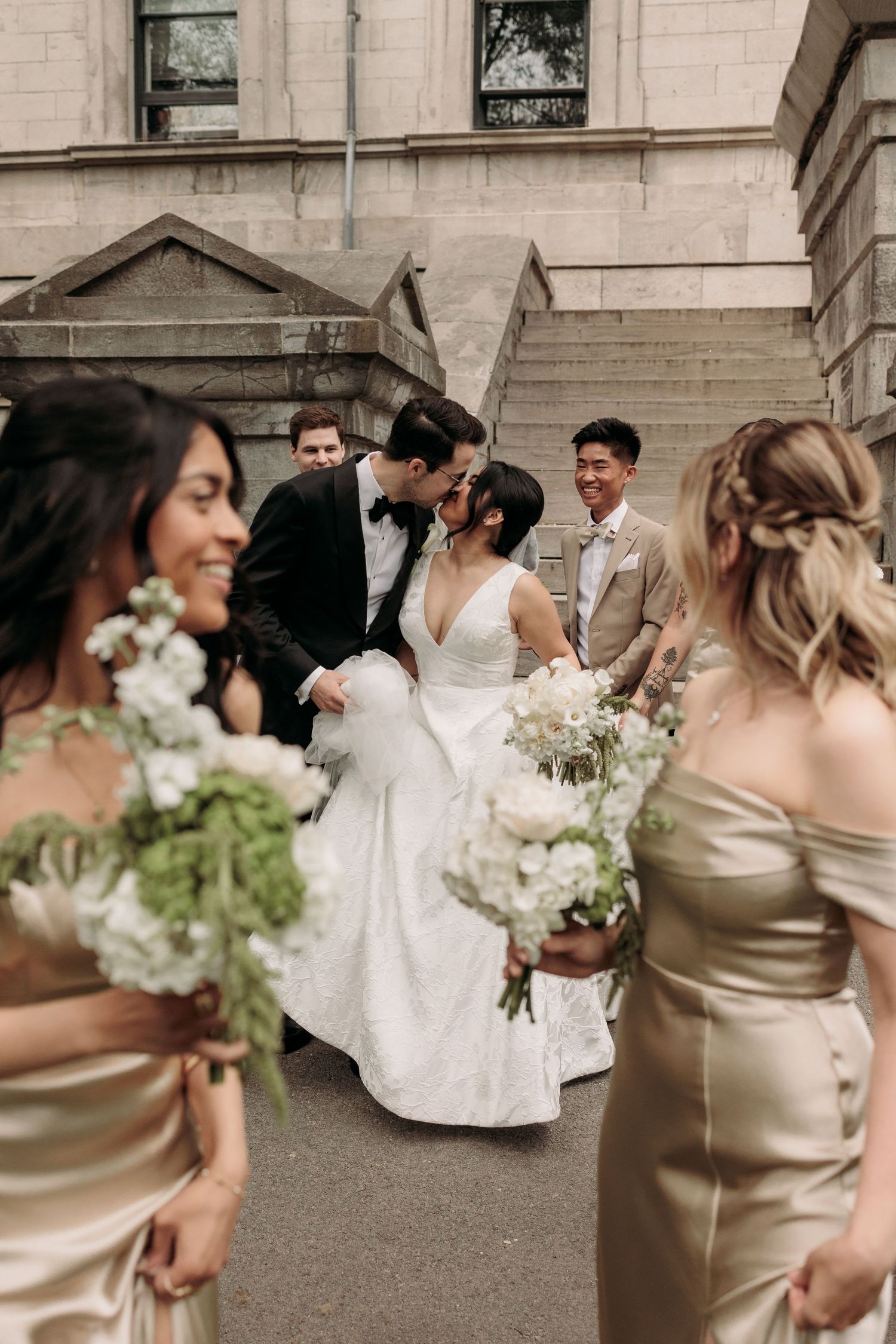 Aliza Dworkind captures the wedding party in champagne-colored bridesmaids dresses and white bridal gown walking together outdoors.