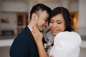 A tender moment between a couple wearing navy and white, with a close embrace showing a sparkly engagement ring.