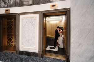 A romantic wedding couple poses together in an elegant elevator during their special day.