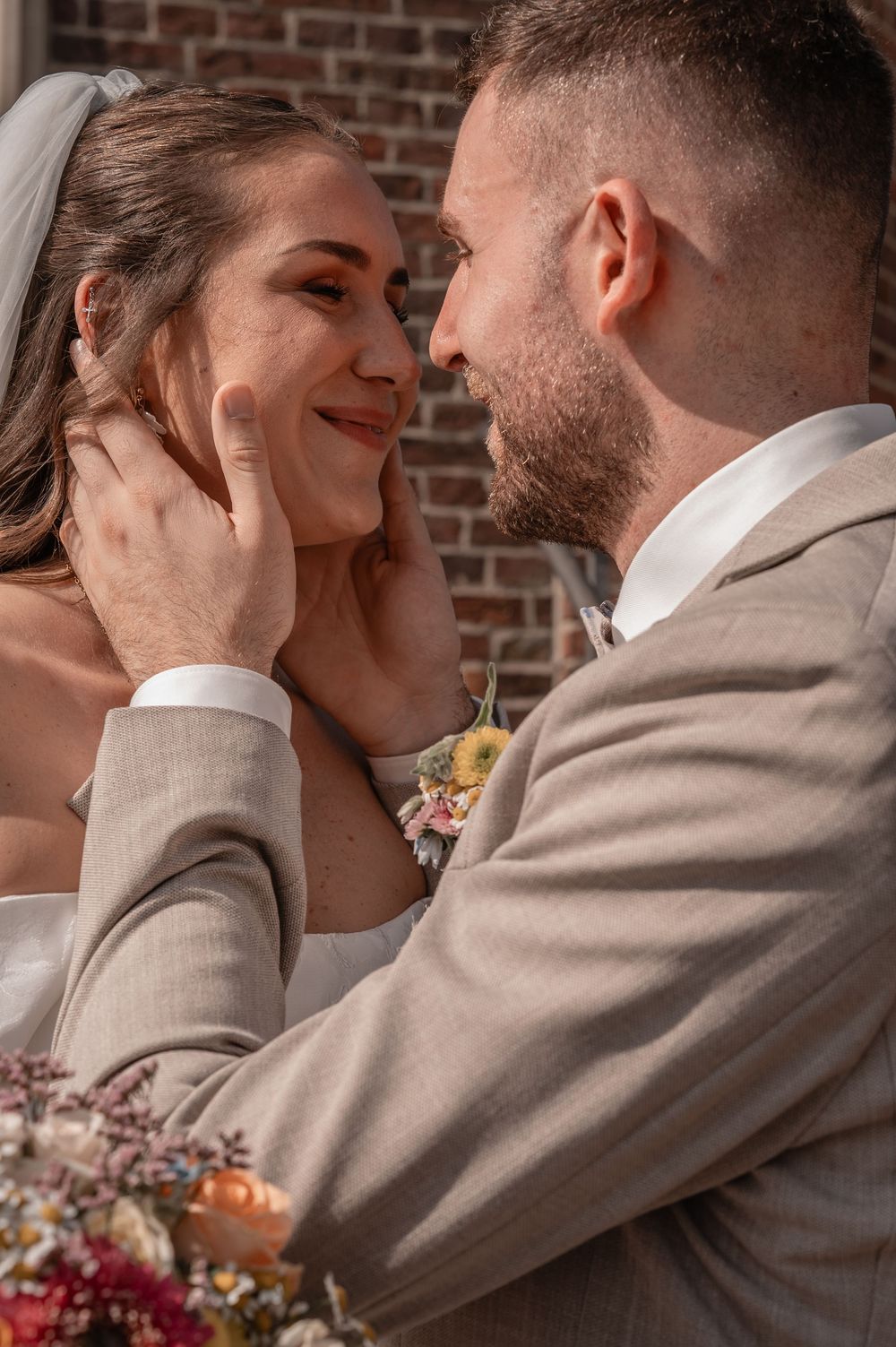 Romantic wedding sequence showing a tender kiss between newlyweds in front of a brick wall.