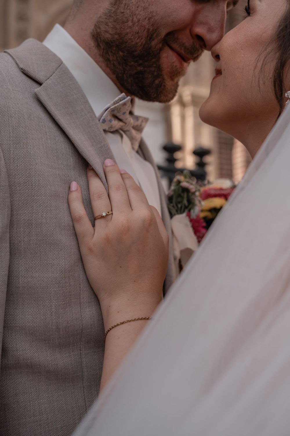 A close-up wedding photo showing an engagement ring and tender moment between newlyweds.