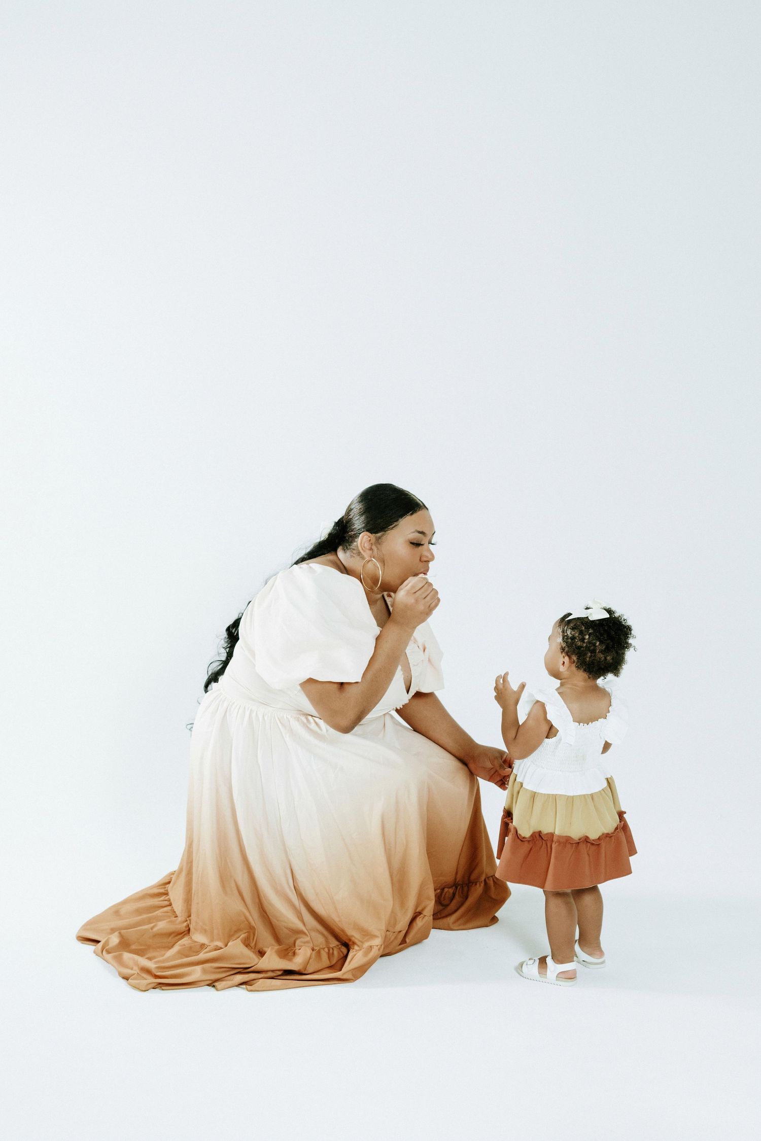 A touching moment shared between two people in coordinated outfits against a white backdrop.