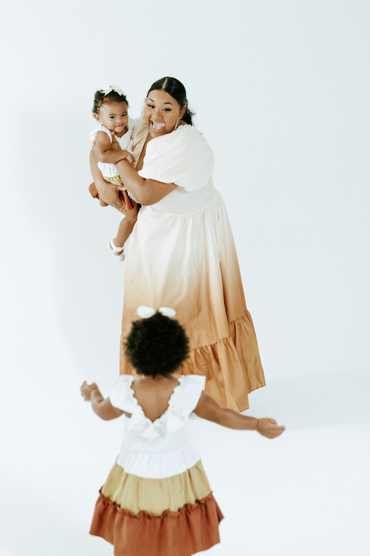 A heartwarming studio photoshoot featuring matching white and brown ombre dresses against a light background.