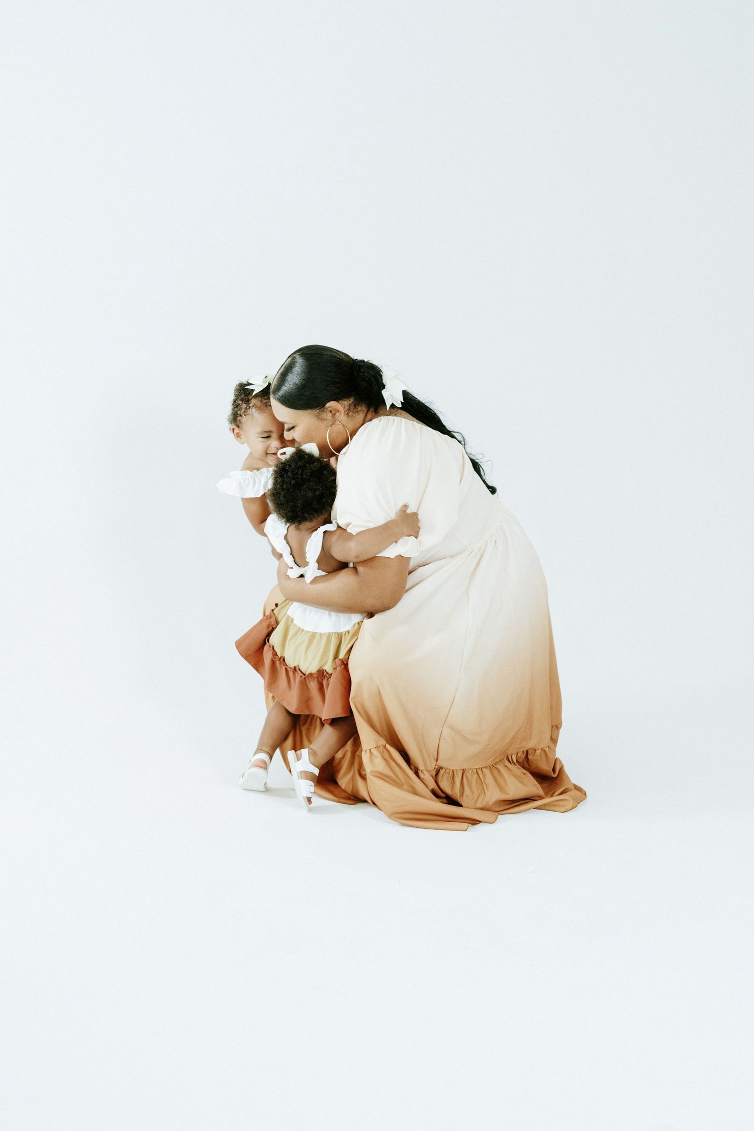 An intimate studio portrait session showcasing coordinated neutral-toned outfits against a white backdrop.