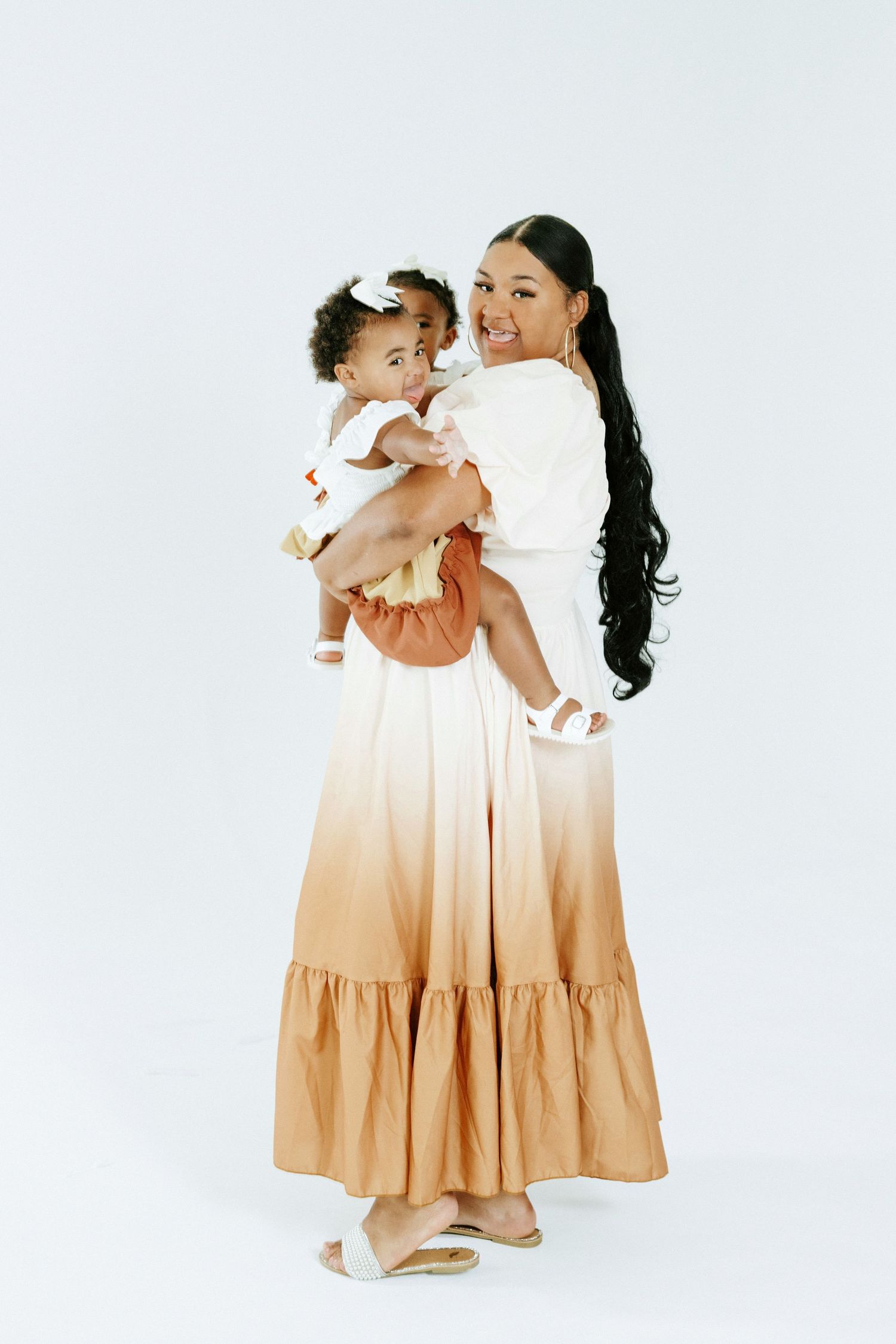Studio photographs showing matching gradient dresses in warm neutral tones against a clean white backdrop.