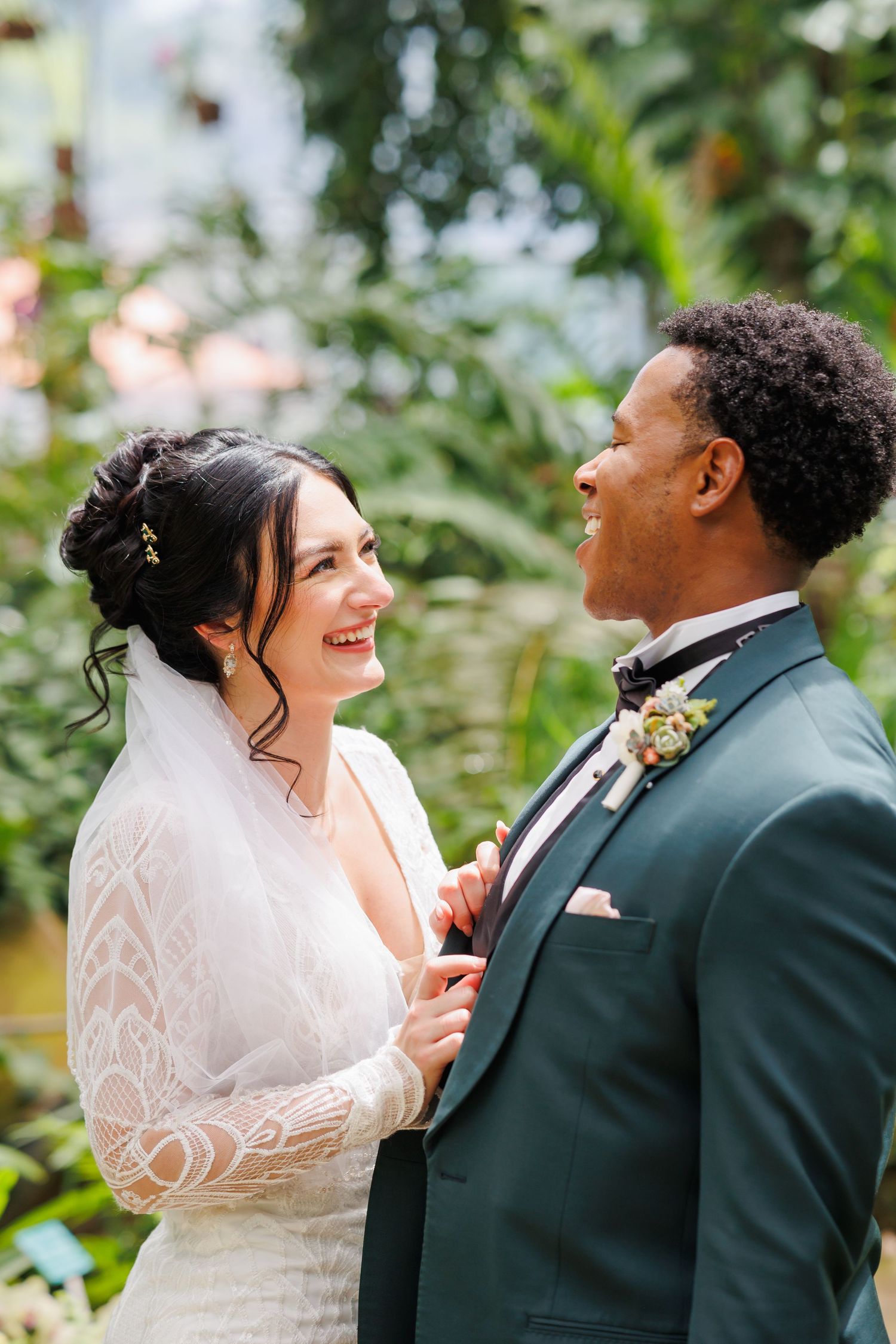 A joyful bride and groom share a candid laughing moment together against a lush garden background.