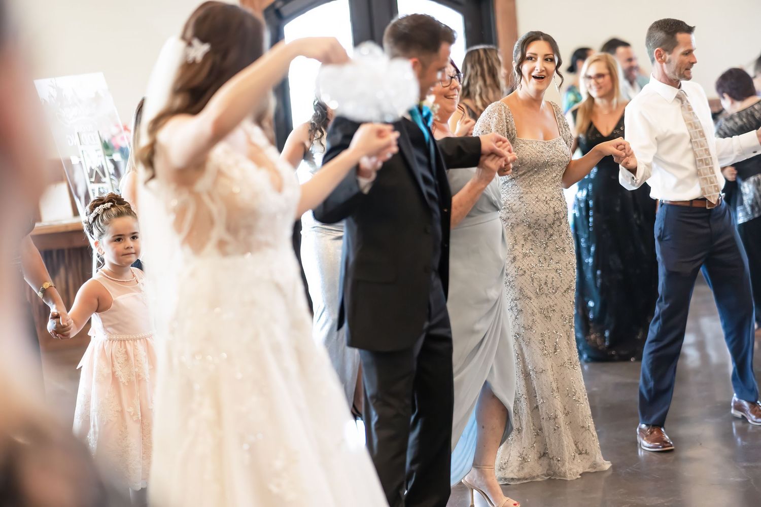 Bride, groom, and wedding guests dance with hands held in a line during a traditional Albanian wedding dance