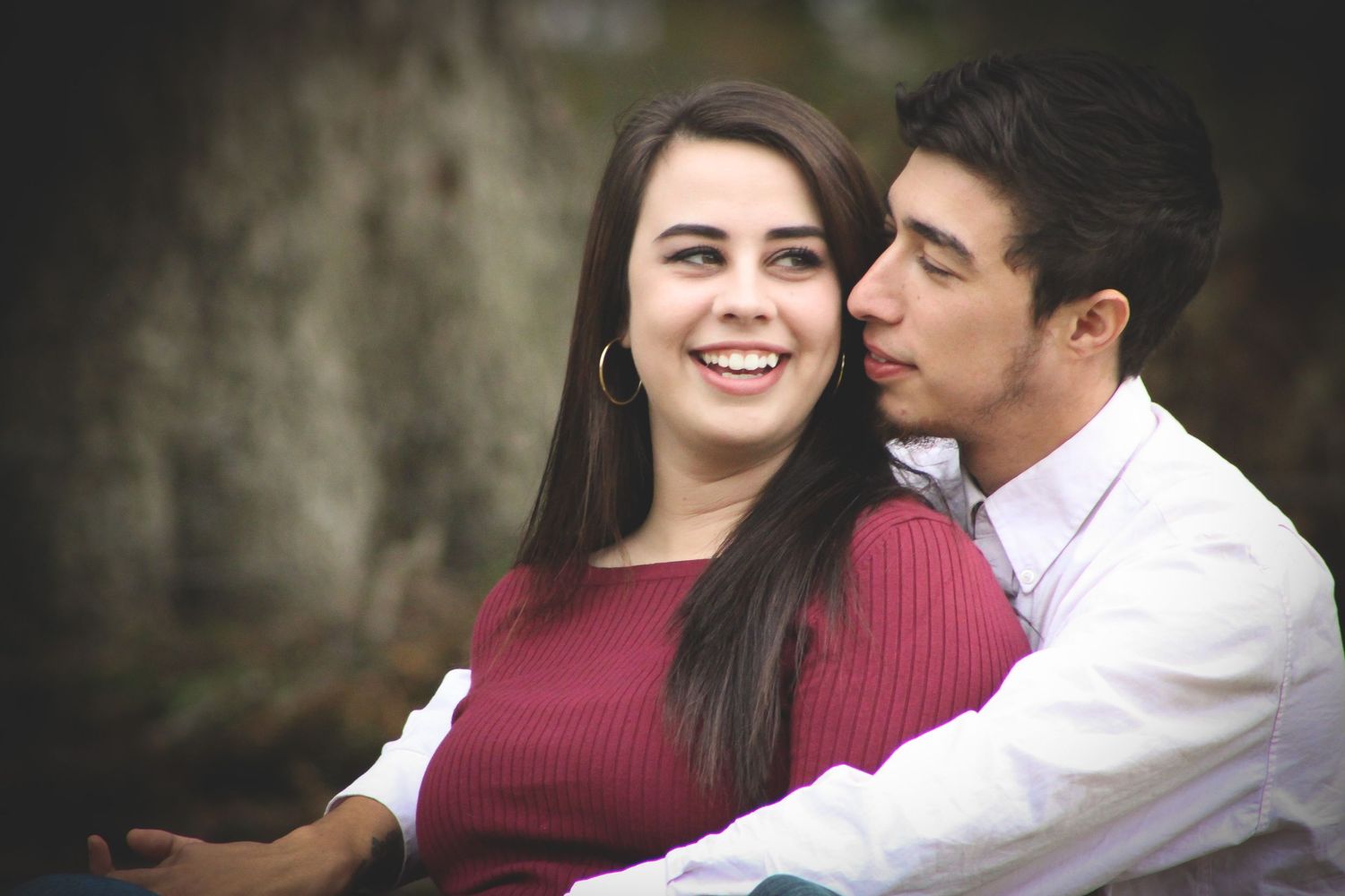 Intimate couple portrait against textured wall background in warm tones.