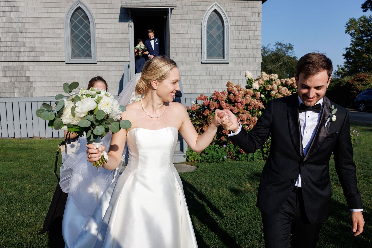 Joyful wedding celebration outside a white stone church with Gothic windows.
