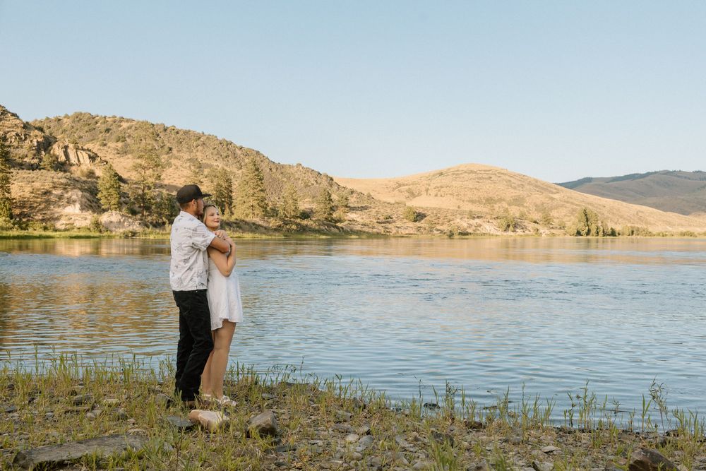 Couple shares intimate moment by scenic mountain lake at sunset.