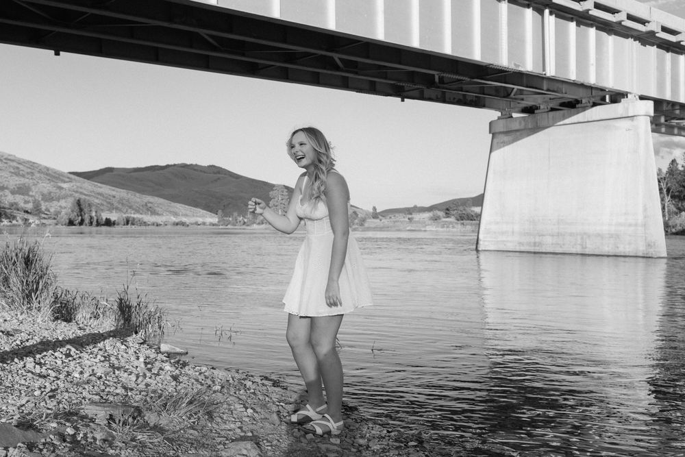 Couple shares tender moments along a serene lakeside with mountain backdrop.